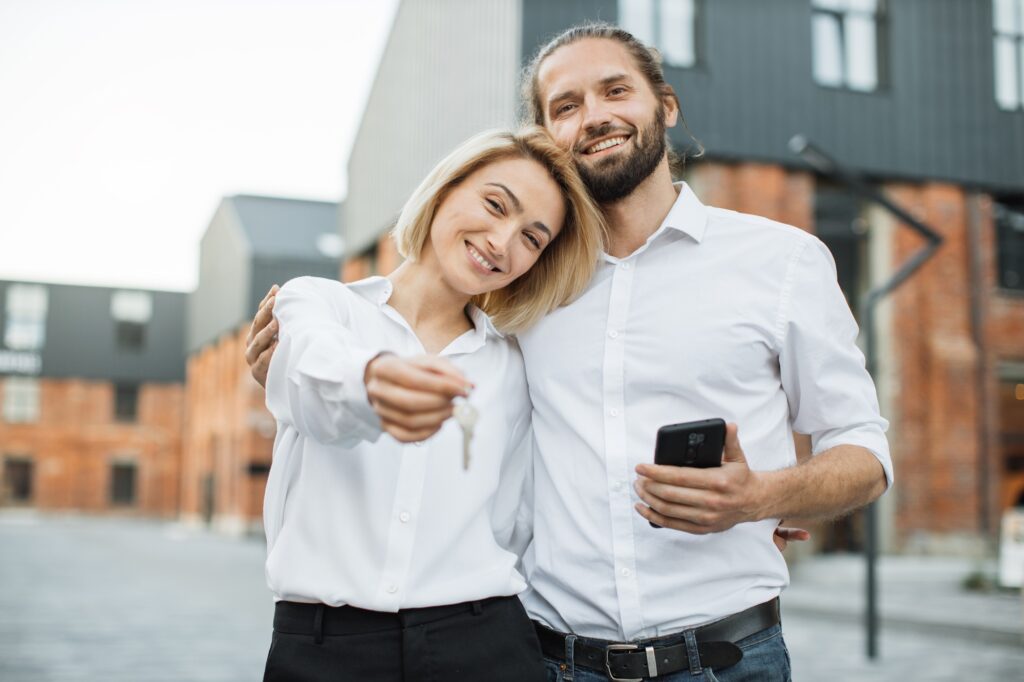 Happy smiling couple showing keys, smiling at camera,